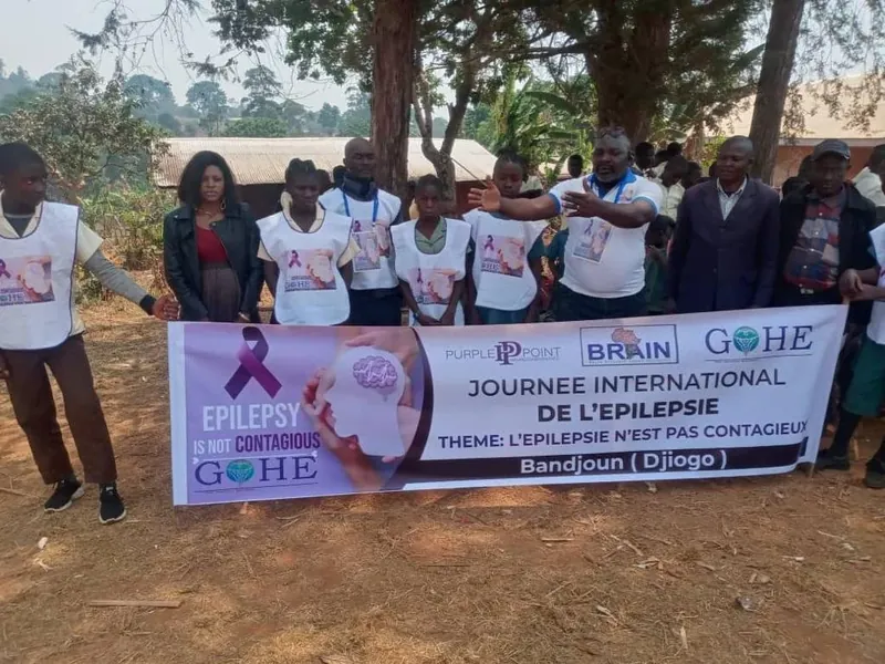 Students and volunteers in Bandjoun, Cameroon, behind a banner that reads Epilepsy is not contagious