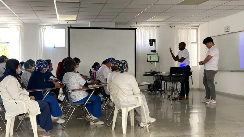 An EEG class in Guatemala: students in scrubs face an instructor beside the EEG equipment